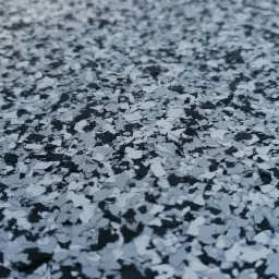 Szczegółowe ujęcie posadzki żywicznej z dekoracyjnymi płatkami w odcieniach szarości i czerni, ukazujące jej teksturę i wykończenie.