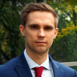 Portret młodego mężczyzny w niebieskim garniturze i czerwonym krawacie na tle zieleni