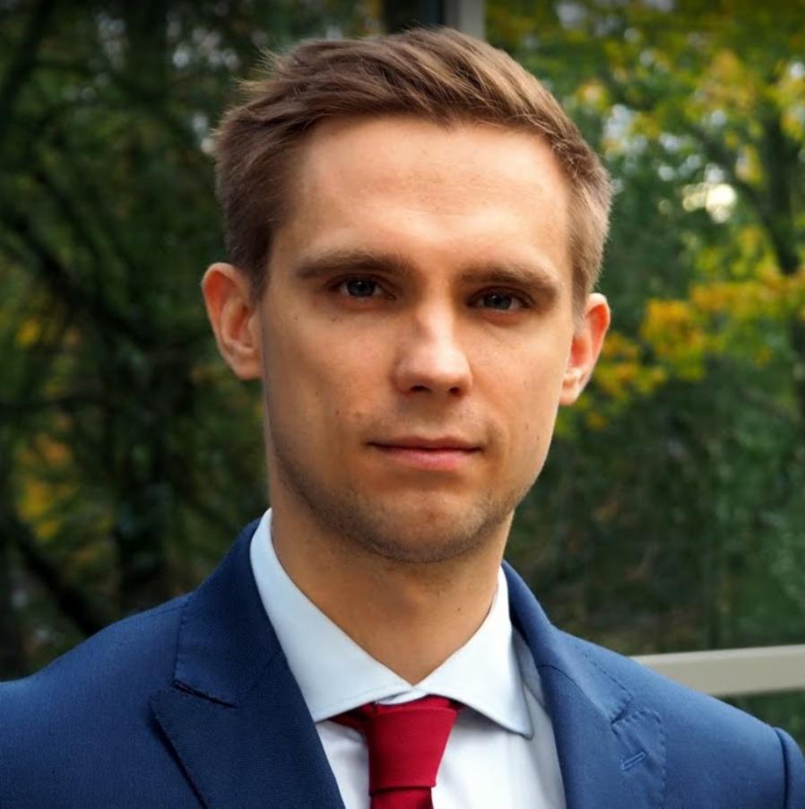 Portret młodego mężczyzny w niebieskim garniturze i czerwonym krawacie na tle zieleni