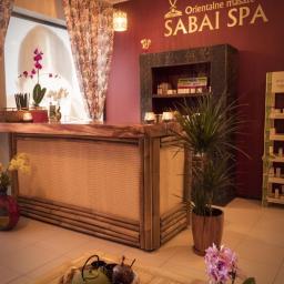 Sabai Spa - Recepcja w orientalnym SPA z bambusowym blatem, widoczne logo 'Sabai SPA' na ścianie, dekoracje roślinne i zestaw do herbaty na stoliku.