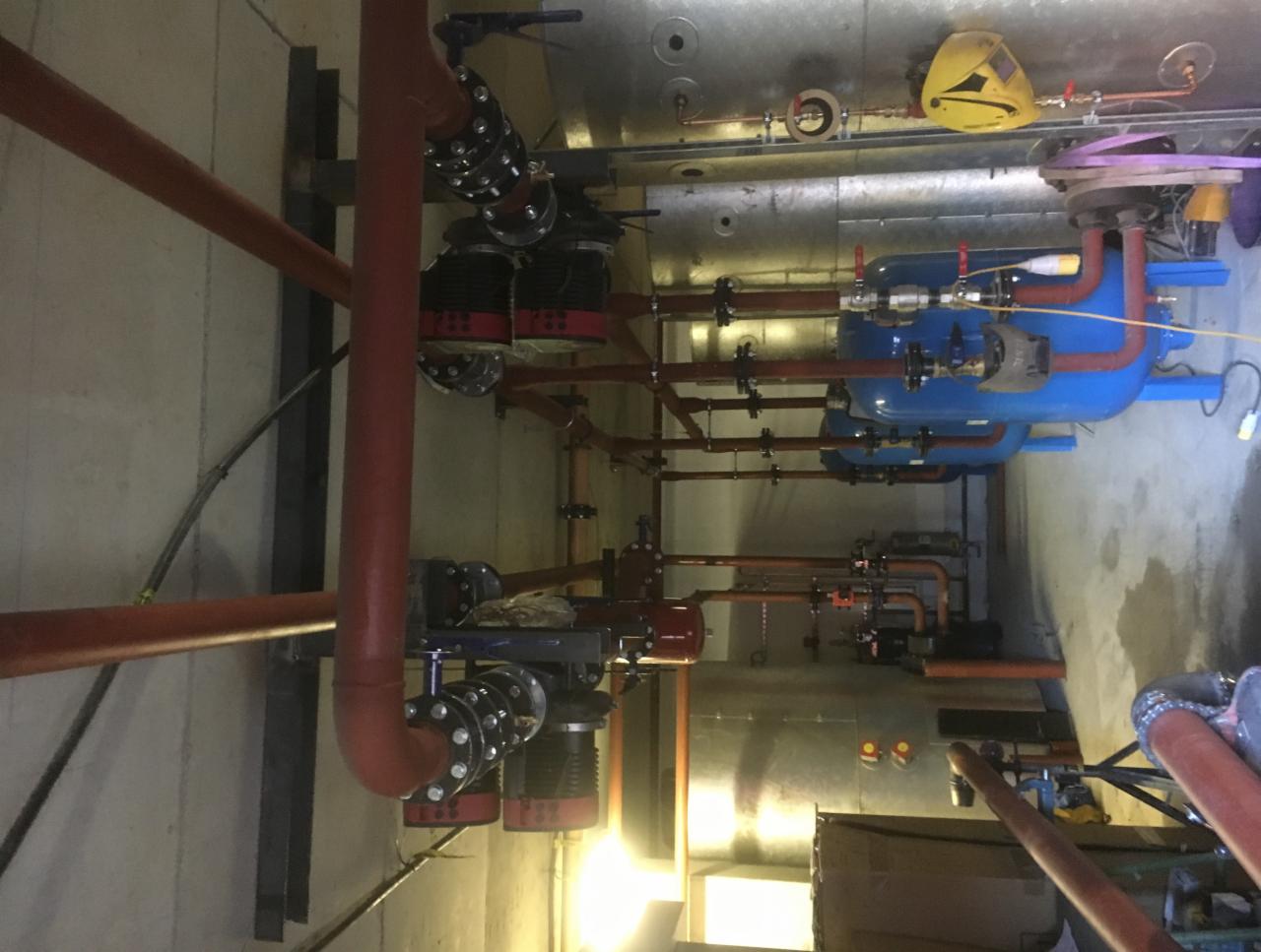 Instalacja przemysłowa z rur, zbiorników ciśnieniowych i zaworów, widok z góry na skomplikowany system rurociągów w pomieszczeniu technicznym.