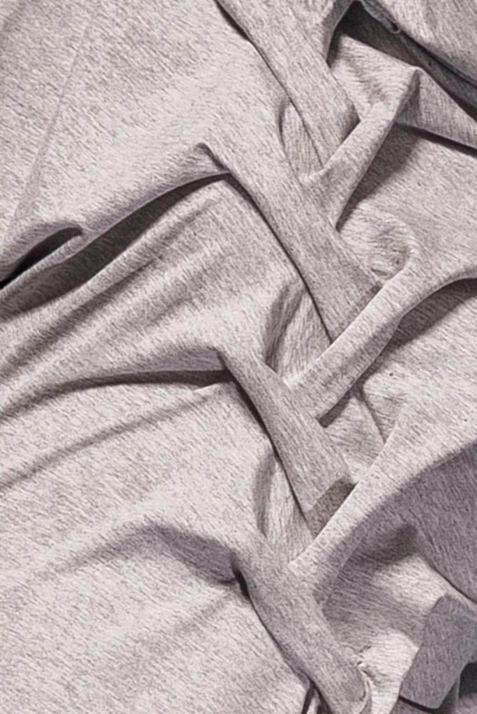 Jasnoszara, melanżowa tkanina dresowa, ułożona w miękkie fałdy i załamania, ukazująca strukturę dzianiny.