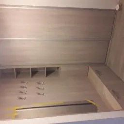 Jasna szafa wnękowa z przesuwnymi drzwiami i wieszakami w Siedlcach, widoczne półki i szuflady, zabezpieczone taśmą malarską podczas montażu lustra.