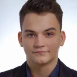 Portret młodego mężczyzny w ciemnej marynarce i niebieskiej koszuli, z krótkimi ciemnymi włosami i jasnymi oczami, na jasnym tle.