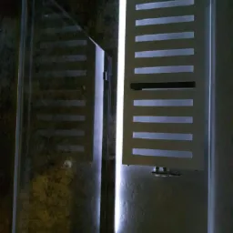 Nowoczesna kabina prysznicowa z grafitową ścianą i podświetlanym panelem grzewczym z poziomymi szczelinami.