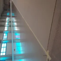 Wnętrze hali produkcyjnej z przygotowaną częścią podłoża pod wylewkę, widoczne taśmy maskujące i gwoździe stabilizujące.