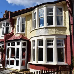 Fasada szeregowca z białymi oknami skrzynkowymi i werandą z numerem 26 w słoneczny dzień.