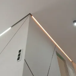 Nowoczesny sufit podwieszany z oświetleniem LED, widok z dołu, geometryczny wzór na ścianie, minimalistyczny design,