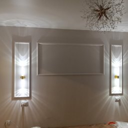 Voytex , Sufity Napinane , Wykonczenia , remonty - Eleganckie wykończenie wnętrza: dekoracyjne listwy ścienne, symetryczne kinkiety z ciepłym światłem i designerski żyrandol w kształcie gwiazdy nad parkietem.