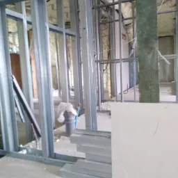 Konstrukcja szkieletowa ścian działowych z profili stalowych, wypełniona pianą izolacyjną, w trakcie prac w Grodzisku Mazowieckim. Widoczne płyty gipsowo-kartonowe przygotowane do montażu.