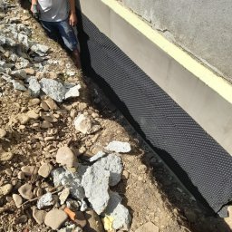 Paweł Lisowicz Usługi Ogólnobudowlane - Fundament zabezpieczony folią kubełkową i ocieplony styrodurem w Gorlicach. Widoczne prace ziemne i przygotowanie do dalszych etapów.