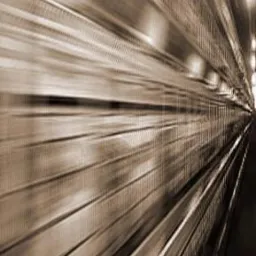 Rozmyte ujęcie metalowej konstrukcji, przypominające wnętrze tunelu lub hali w trakcie budowy, sfotografowane z dynamicznej perspektywy z efektem rozmycia w ruchu.