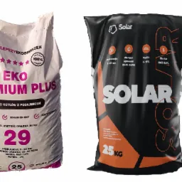 Dwa worki opału: biały worek z napisem 'EKO PREMIUM PLUS' i czarny worek z napisem 'SOLAR', oba o wadze 25 kg, przeznaczone do kotłów z podajnikiem.