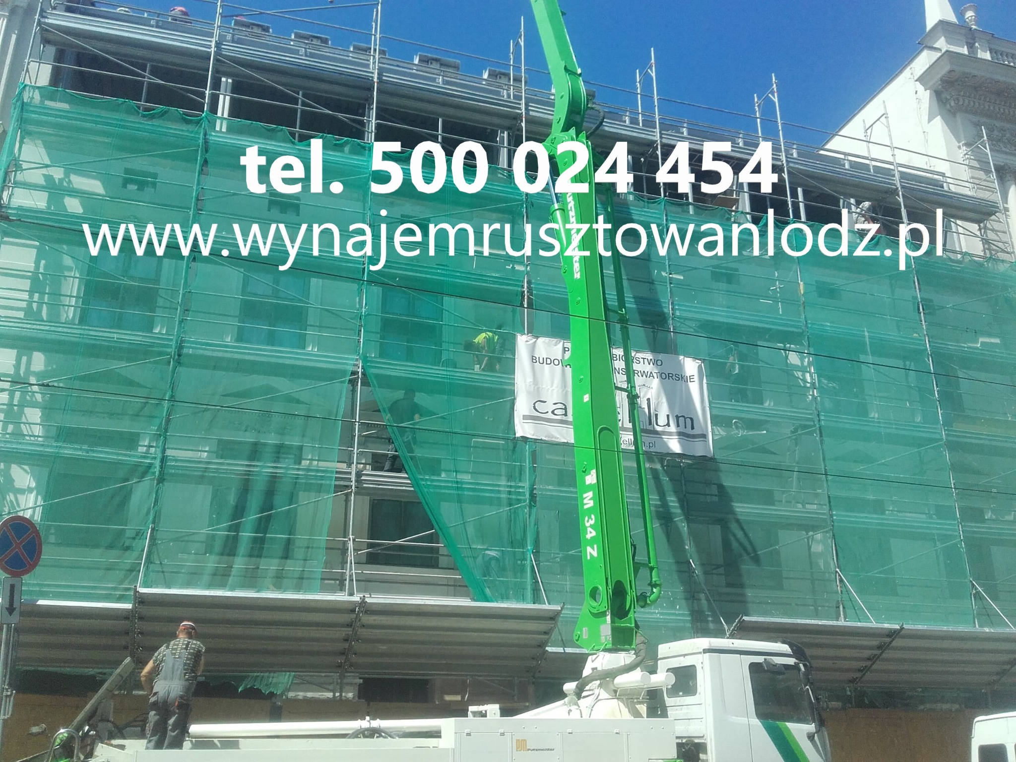 Elewacja budynku w rusztowaniach, zabezpieczona siatką. Na pierwszym planie wysięgnik pompy do betonu. Widoczny pracownik na rusztowaniu.