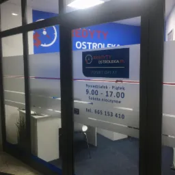 Wejście do biura kredytowego w Ostrołęce, z widocznym logo firmy, godzinami otwarcia i numerem telefonu na szybie.