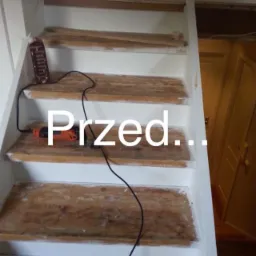 Schody drewniane w trakcie renowacji, widoczna szlifierka oscylacyjna i częściowo usunięta stara powłoka, białe boki schodów, widok z góry na kilka stopni.