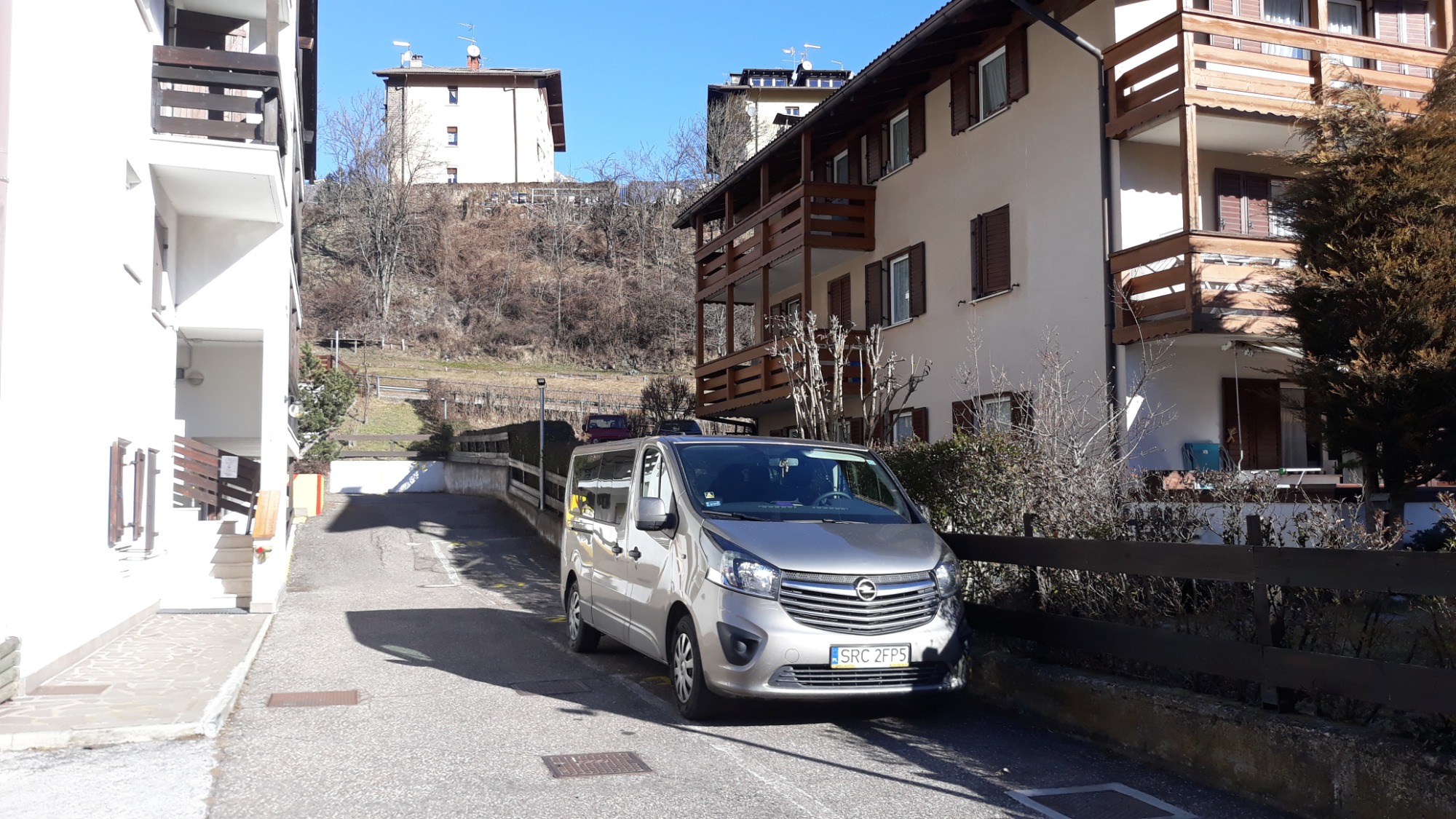 Srebrny van Opel Vivaro zaparkowany na wąskiej, spadzistej ulicy z budynkami w tle, widok z dołu.