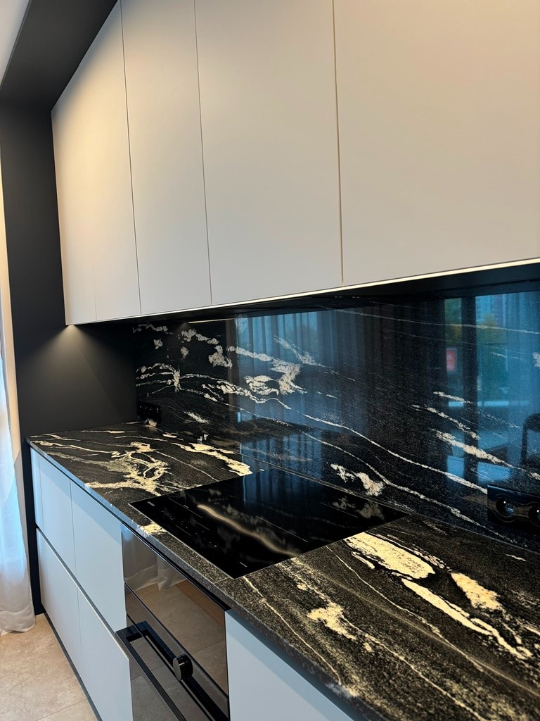 Czarno-biały blat kamienny z wbudowaną płytą grzewczą, eleganckie wykończenie kuchni w Warszawie. Unikalny wzór kamienia i nowoczesny design.