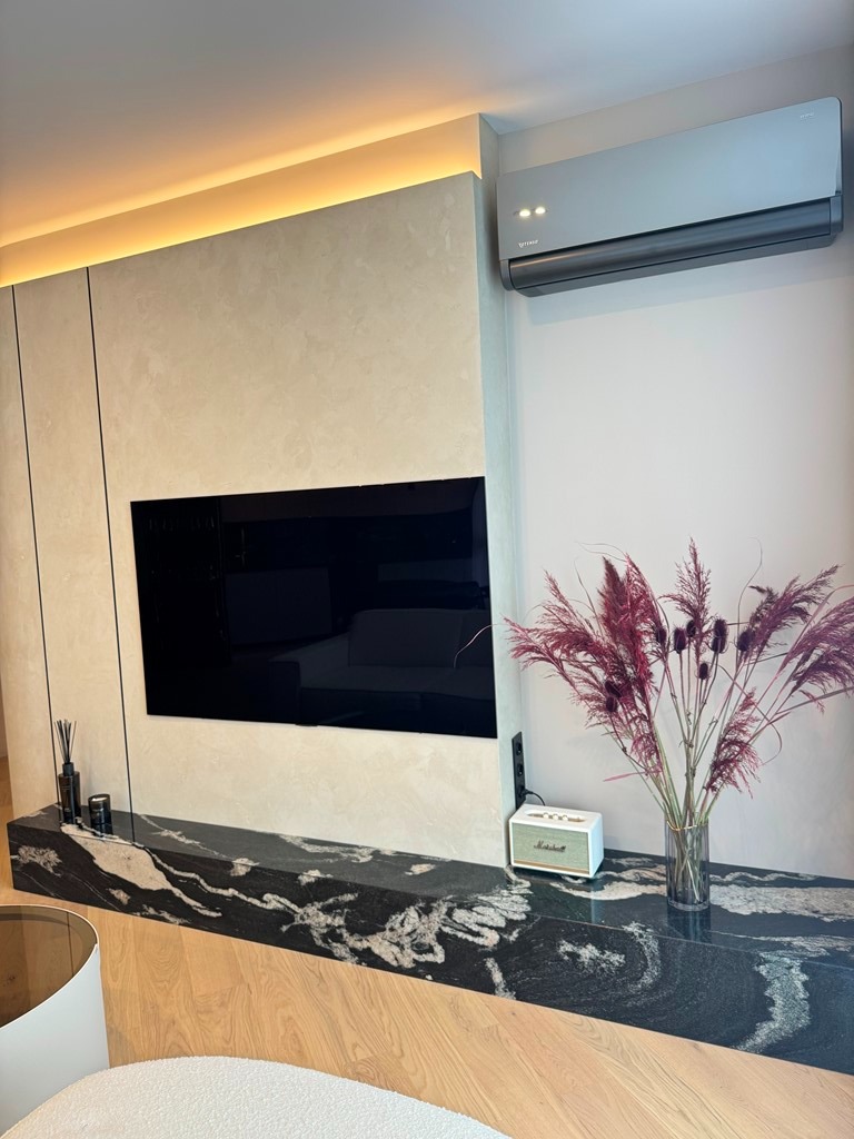 Czarny blat kamienny pod telewizorem z unikalnym wzorem żyłkowania, dopasowany do nowoczesnego wnętrza z oświetleniem LED. Elegancki detal wykończenia.