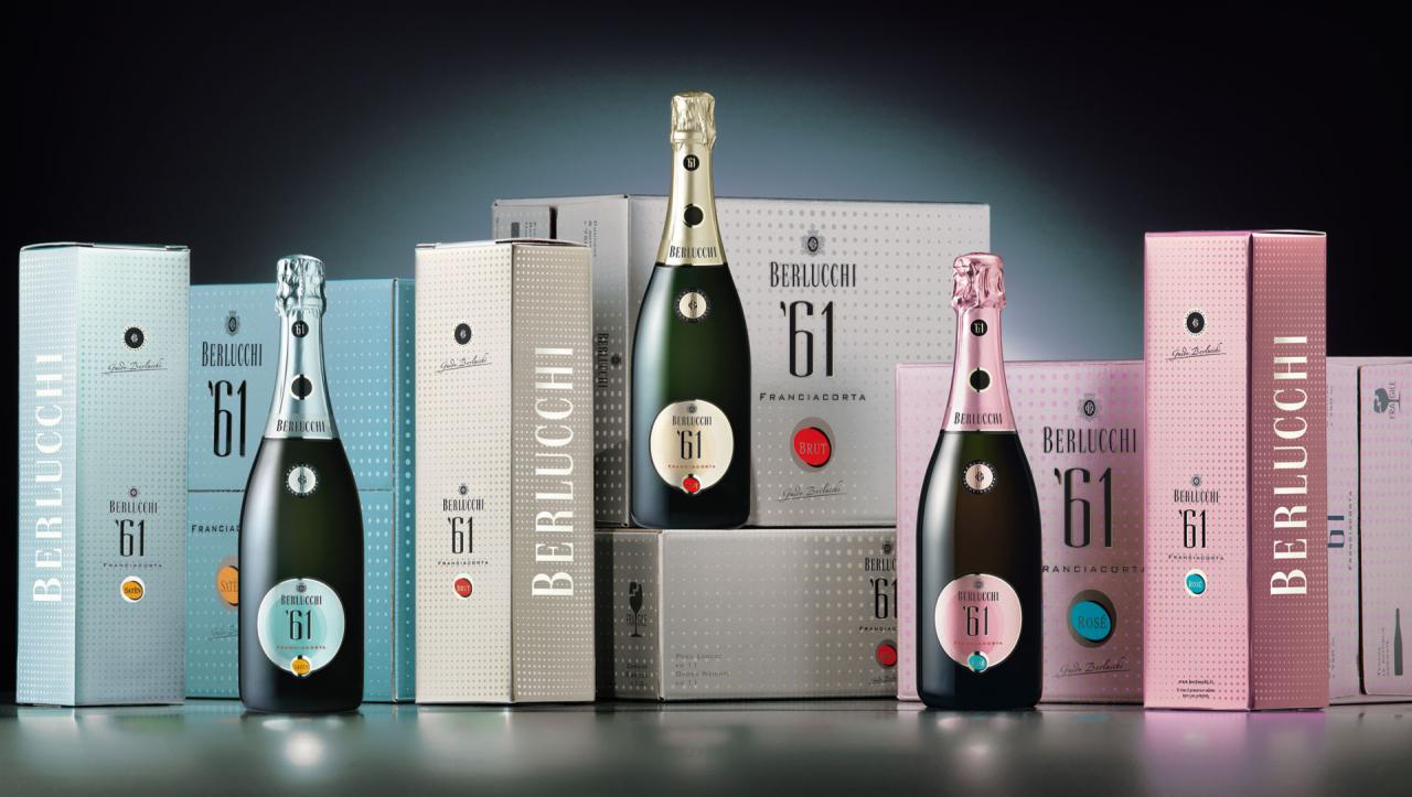 Elegancka prezentacja trzech rodzajów wina musującego Berlucchi '61 Franciacorta w butelkach i dopasowanych kolorystycznie pudełkach, z etykietami Brut, Satèn i Rosé, na ciemnym tle.