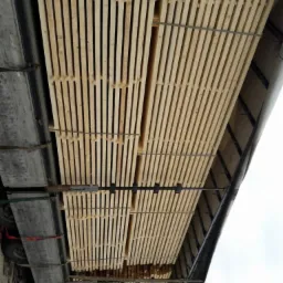 Transport drewna: Jasne, świeżo przetarte deski ułożone w stosy na przyczepie ciężarówki, zabezpieczone taśmami.