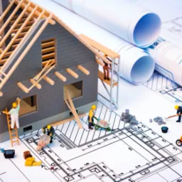 Model domu murowanego w trakcie budowy, z widocznymi elementami konstrukcyjnymi, planami architektonicznymi i miniaturowymi robotnikami przy pracy.
