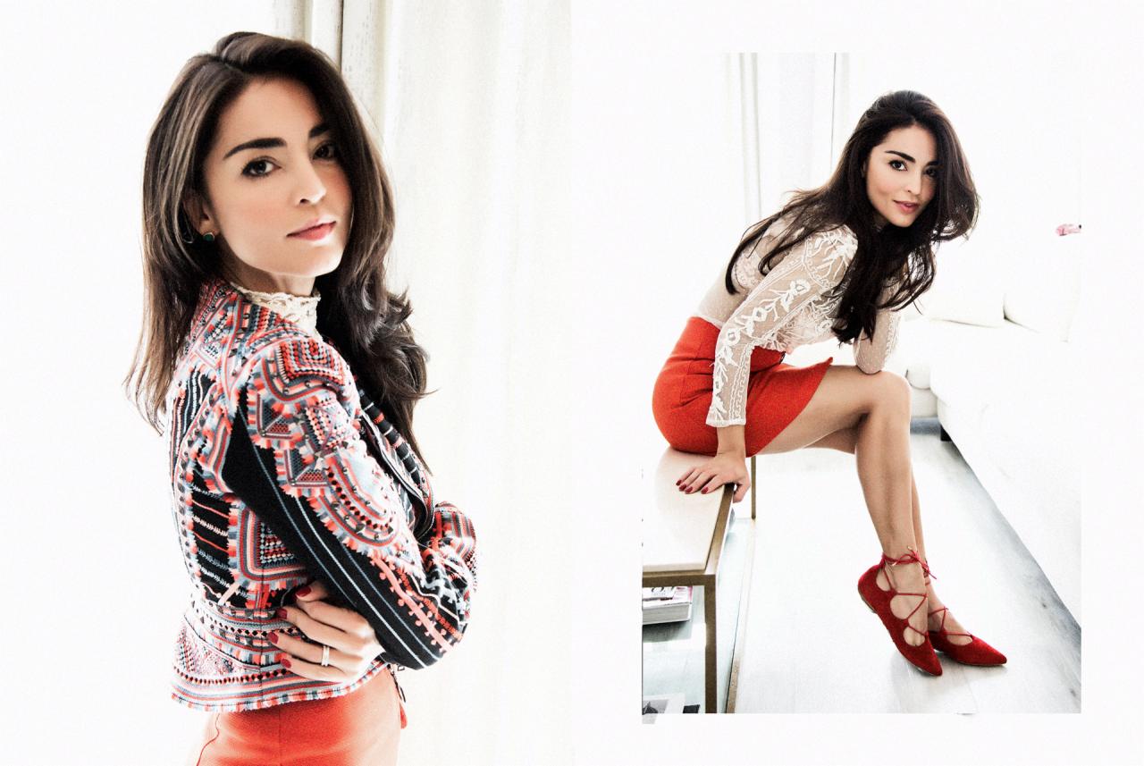 Portret kobiety w kolorowej kurtce i czerwonej spódnicy, na drugim planie siedząca postać w koronkowej bluzce i czerwonych butach na tle białej sofy.