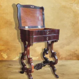 Antyczny, ciemnobrązowy sekretarzyk z dwoma szufladami i otwartą klapą, ozdobne nogi, stylizowane tło.