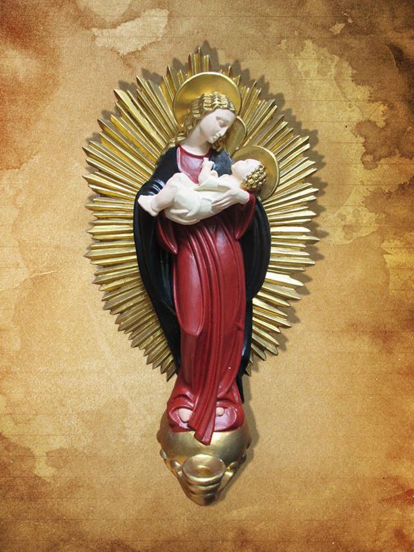 Ręcznie rzeźbiona, polichromowana figura Matki Boskiej z Dzieciątkiem, otoczona złoconymi promieniami, umieszczona na tle beżowej ściany o fakturze przypominającej stary pergamin.