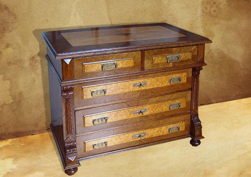 Drewniana komoda z czterema szufladami, intarsjowana na frontach i blacie, z ozdobnymi rzeźbieniami po bokach.