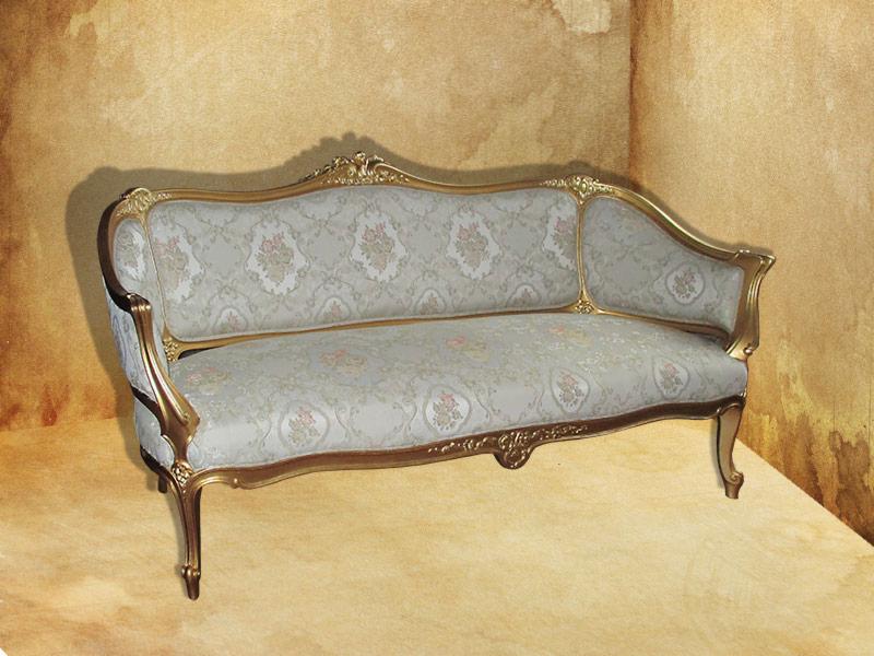 Antyczny szezlong z złoconymi zdobieniami i tapicerką w kwiatowy wzór, wykonany przez tapicera z Wrocławia, ustawiony w rogu pokoju z teksturowanymi ścianami.