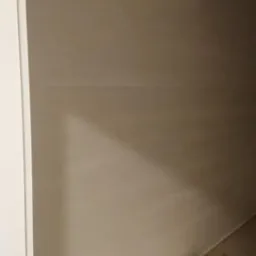 Ściana po nałożeniu warstwy wykończeniowej w Rokitach, widoczne delikatne smugi i równomierne oświetlenie, przygotowana do dalszych prac.