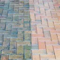 Mobilna Myjnia Mycie Pełną Parą - Częściowo wyczyszczona kostka brukowa ułożona we wzór jodełki; widoczna wyraźna różnica w kolorze między czystą, jasną częścią a zabrudzoną, ciemniejszą.