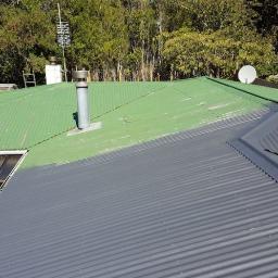 Mobilna Myjnia Mycie Pełną Parą - Częściowo pomalowany blaszany dach: zielona, stara część z kominem i szara, nowa część. W tle drzewa.