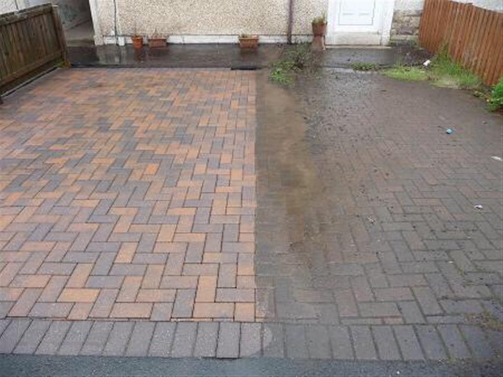 Częściowo umyta kostka brukowa na podjeździe przed domem, widoczna wyraźna różnica w kolorze i czystości między umytą a nieumytą powierzchnią.