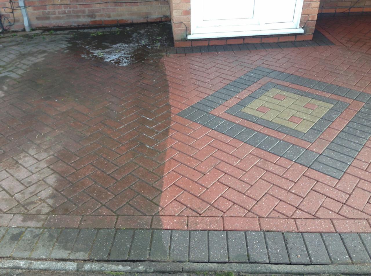 Częściowo wyczyszczona kostka brukowa przed domem, widoczna wyraźna różnica w kolorze i czystości między umytą a brudną powierzchnią.
