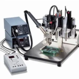 Automatyczna stacja lutownicza Weller WMD-200 z precyzyjnym ramieniem i panelem sterowania, lutująca płytkę drukowaną na metalowym stole.