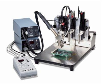 Automatyczna stacja lutownicza Weller WMD-200 z precyzyjnym ramieniem i panelem sterowania, lutująca płytkę drukowaną na metalowym stole.
