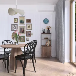 Jadalnia w jasnych barwach z okrągłym, drewnianym stołem i czarnymi krzesłami w stylu wiedeńskim. Na ścianie galeria obrazków i półka z książkami. Parkiet ułożony w jodełkę.