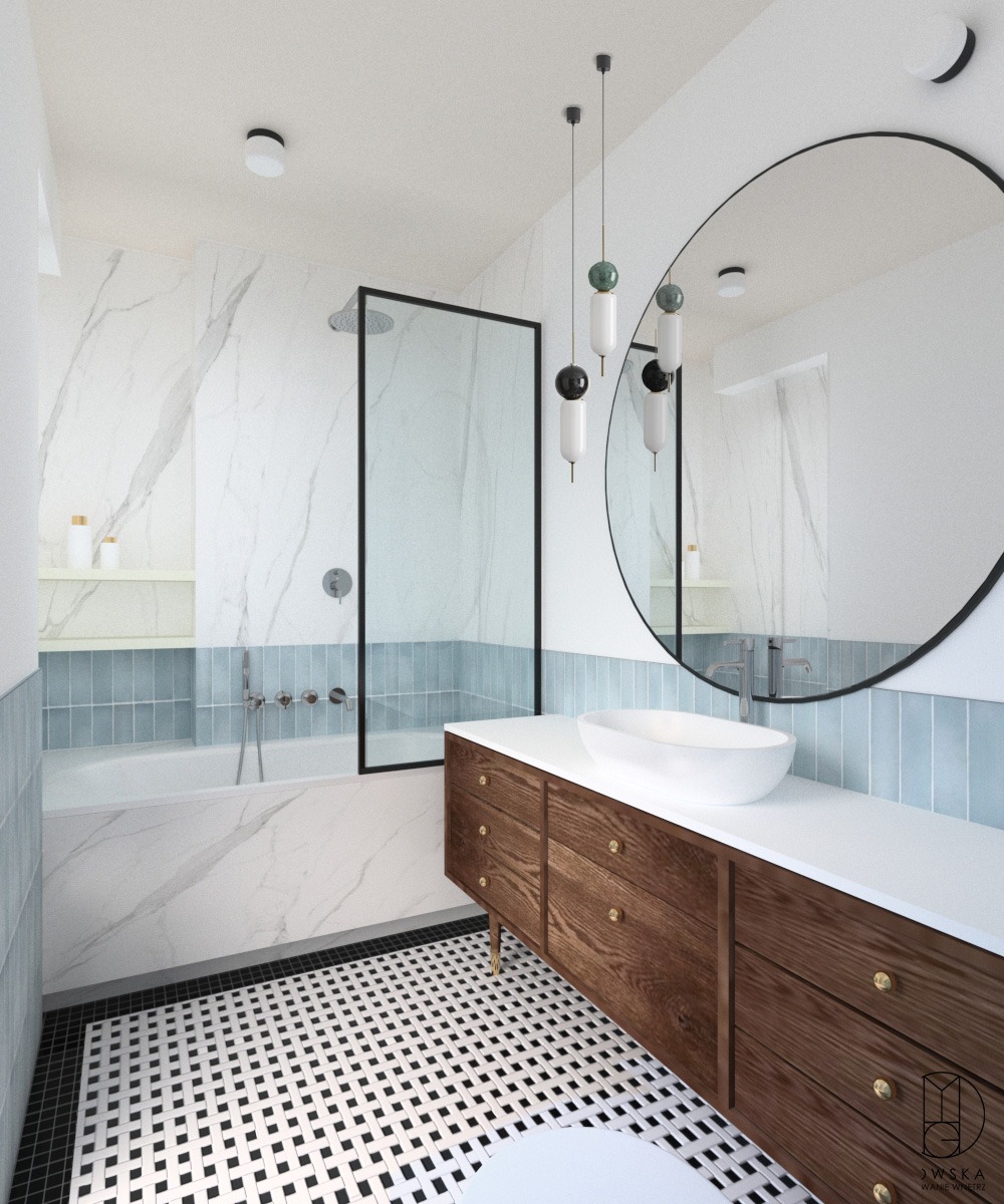 Nowoczesna łazienka z marmurowymi ścianami, błękitnymi akcentami w postaci płytek, czarno-białą mozaiką na podłodze, drewnianą szafką pod umywalkę i okrągłym lustrem.