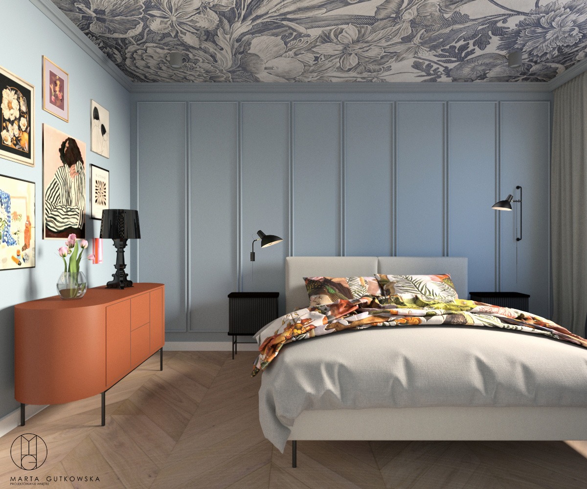 Sypialnia w odcieniach błękitu z wzorzystą tapetą na suficie, pomarańczowa komoda z czarną lampą, łóżko z kolorową pościelą, parkiet w jodełkę.