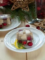 Tymbaliki z żurawiną na białym talerzu, udekorowane cytryną i koperkiem, w tle świąteczna dekoracja z gałązek i gwiazdek.