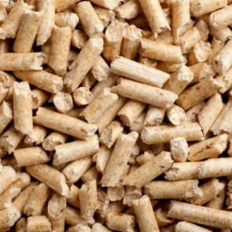 Jasne, cylindryczne brykiety pelletu drzewnego ułożone blisko siebie, wypełniające kadr. Widoczna struktura włókien drewna i nieregularne krawędzie pelletu.