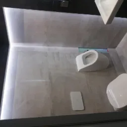 Nowoczesna łazienka z szarą płytką imitującą beton, podświetleniem LED i podwieszanymi sanitariatami: muszla klozetowa, bidet i umywalka.