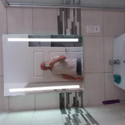 Nowoczesna łazienka z podświetlanym lustrem, białą umywalką i mozaiką w odcieniach szarości, widoczny fragment mopa.