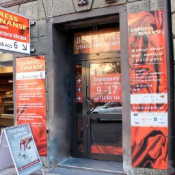 Fasada budynku z szyldem 'Express Finanse', informacją o bezpłatnych usługach finansowych i zaproszeniem od poniedziałku do piątku w godzinach 9-17, dodatkowo reklama 'Przyciągnij gotówkę'.
