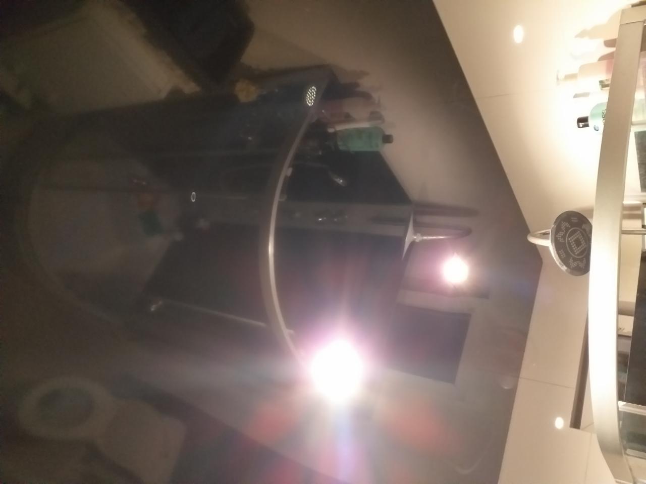 Nowoczesna kabina prysznicowa z czarnym brodzikiem, chromowanymi elementami i oświetleniem punktowym, widziana z nietypowej perspektywy.