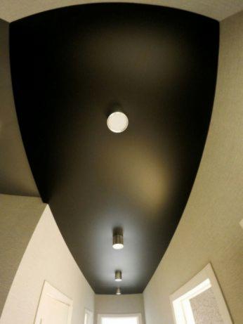 Czarny, matowy sufit napinany z rzędem punktowych lamp w korytarzu, widok z dołu.