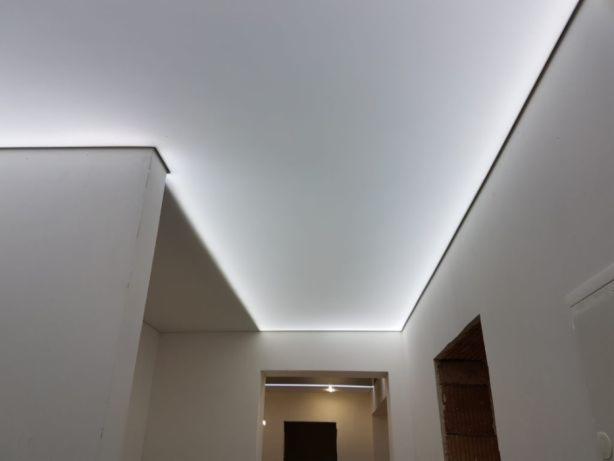 Biały, podświetlany sufit napinany z widocznym oświetleniem LED wzdłuż krawędzi, perspektywa z dołu.