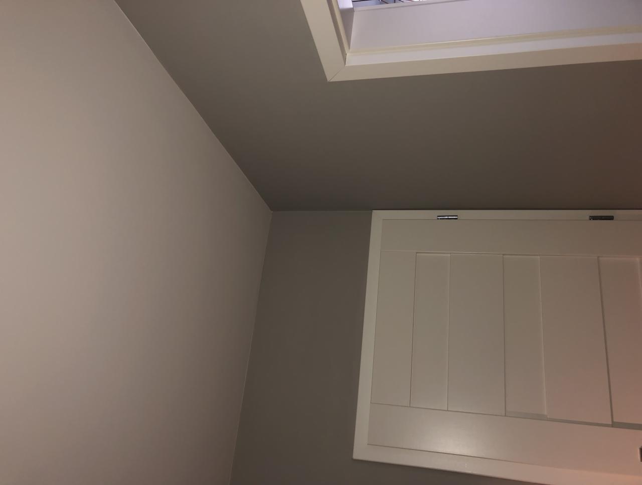 Ściana pod skosem pomalowana na dwa odcienie szarości, z widocznym włazem strychowym w białej ramie.